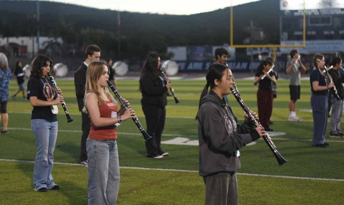 Celine Njuyen (11), Lily Lander (9), and Jasmine Riddley (12) take center field while band rehearsal learns a new piece. Each section of brass, melody, bass, and percussion took time to write down what step is next, going piece by piece of the new song. 