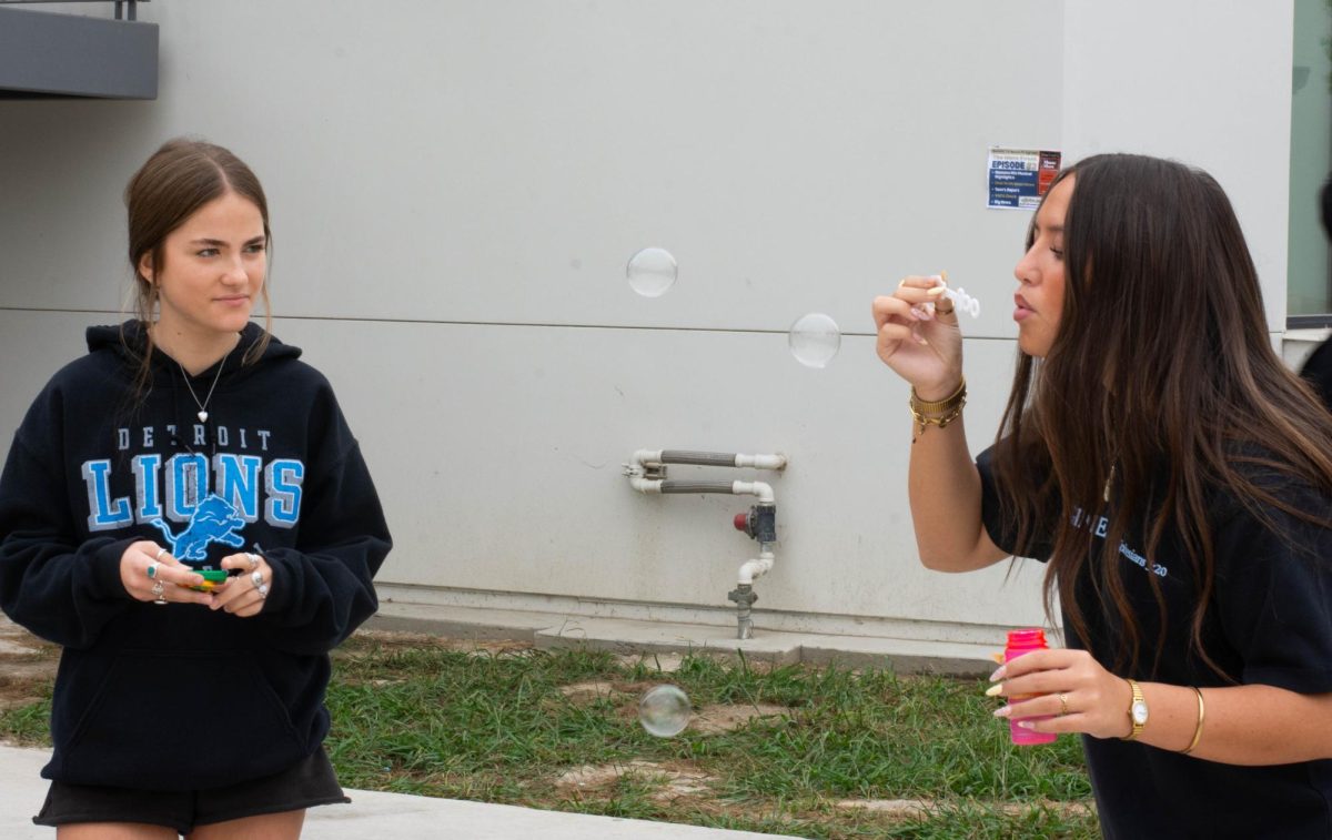 Student Lexi Lau (11) carefully blows a bubble while student Chelsea Shady (11) watches during the “Bubble Babies” lab in Mrs. Price’s AP Environmental Science class. The students worked to see how long their bubble lasts, representing survival curves of offspring. 