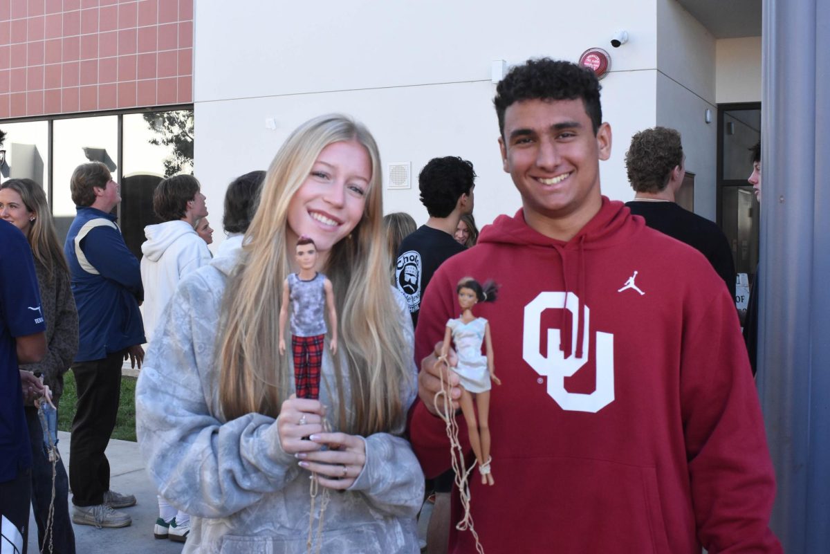 Kenna Maguire (12) and Gavin Malone (12) pose with their barbies they use for their Intro to Statistics class. For their project each group drops a barbie from the stairs of J building in order to calculate how many rubber bands are needed to drop the barbie without it hitting the ground.