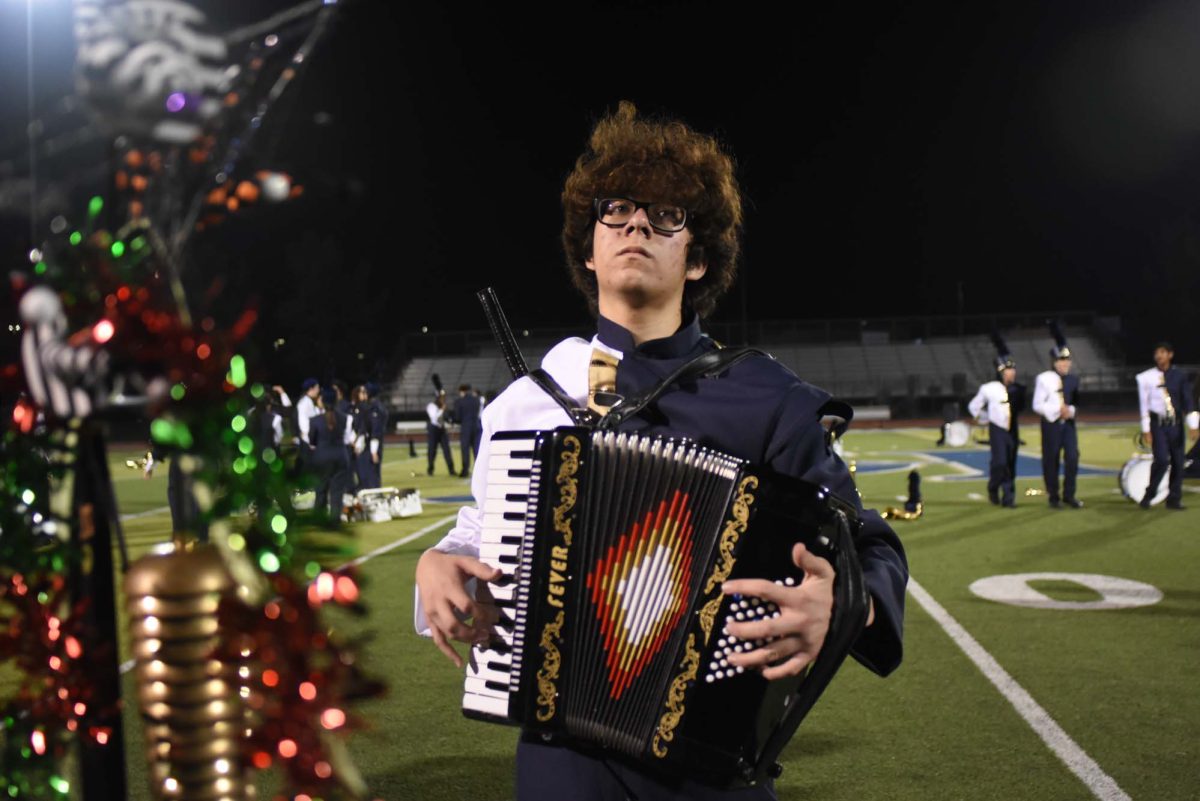 Holding the accordion, Ryan Waung (12) is ready to play for the start of a section. He learned the accordion on his own time for the performance as well as writing part of the orchestra pits’ notes.