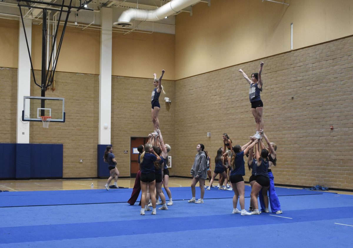 The cheer squad works together, trust and teamwork taking center stage as they practice high-level stunts in the gym. 
