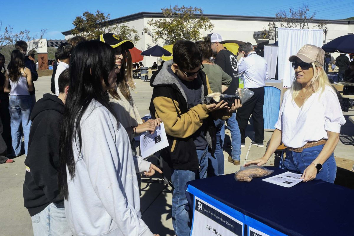 Anatomy & Physiology teacher Rita Kolenic hands off the preserved cat to students as she elaborates on what the anatomy & physiology elective is about. The elective fair is an annual event that allows students to interview what electives are available to pick for their classes next year and what graduation requirements they complete.