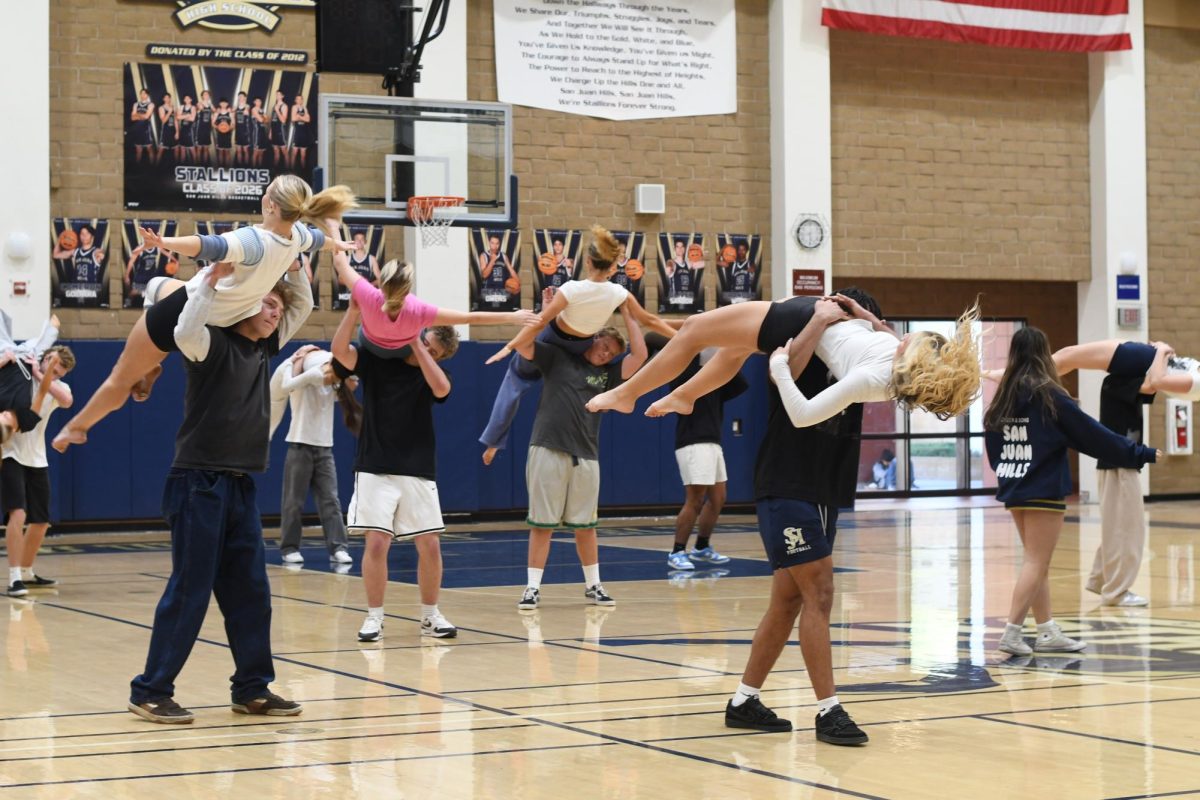 During rehearsal, dancers are flipped in the air by their partners in preparation for the Winter Formal pep rally. The powerful lifts show cohesion and precision, properly setting the tone for the pep rally.