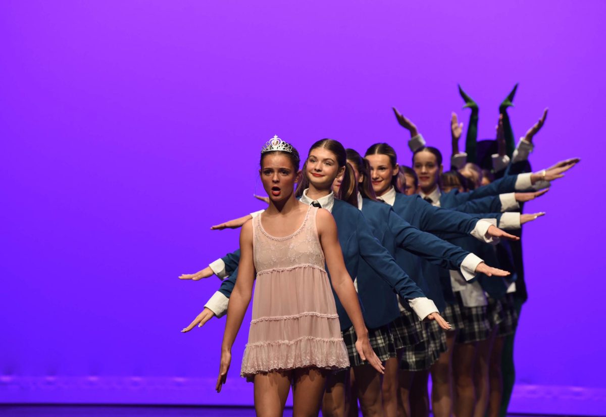 In the Wicked performance, the Good Witch or Glinda is played by Kaela Bullock (9) as she stands in the center of the stage as her classmates surround her and frame her with their arms. Bullock has the same bubbly personality as Glinda throughout the performance, and really brings the dance to life.