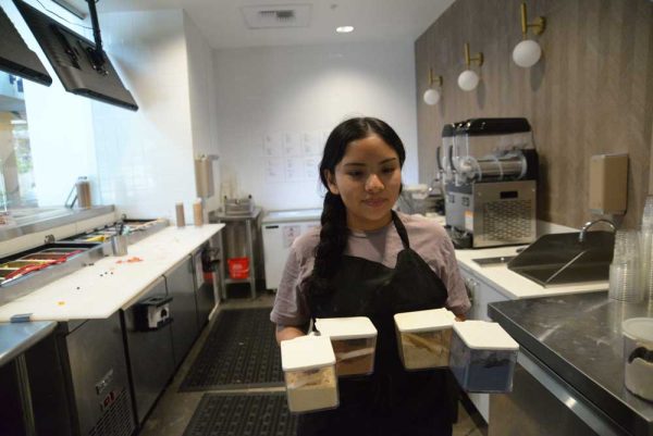 Madison Perez (12) heads to the back room to clean up powdered ingredients used for some smoothies and bowls made at Palmetto Superfoods, River Street Marketplace. Behind her is the kitchen that customers can see their smoothies and acai bowls being made in front of them. 