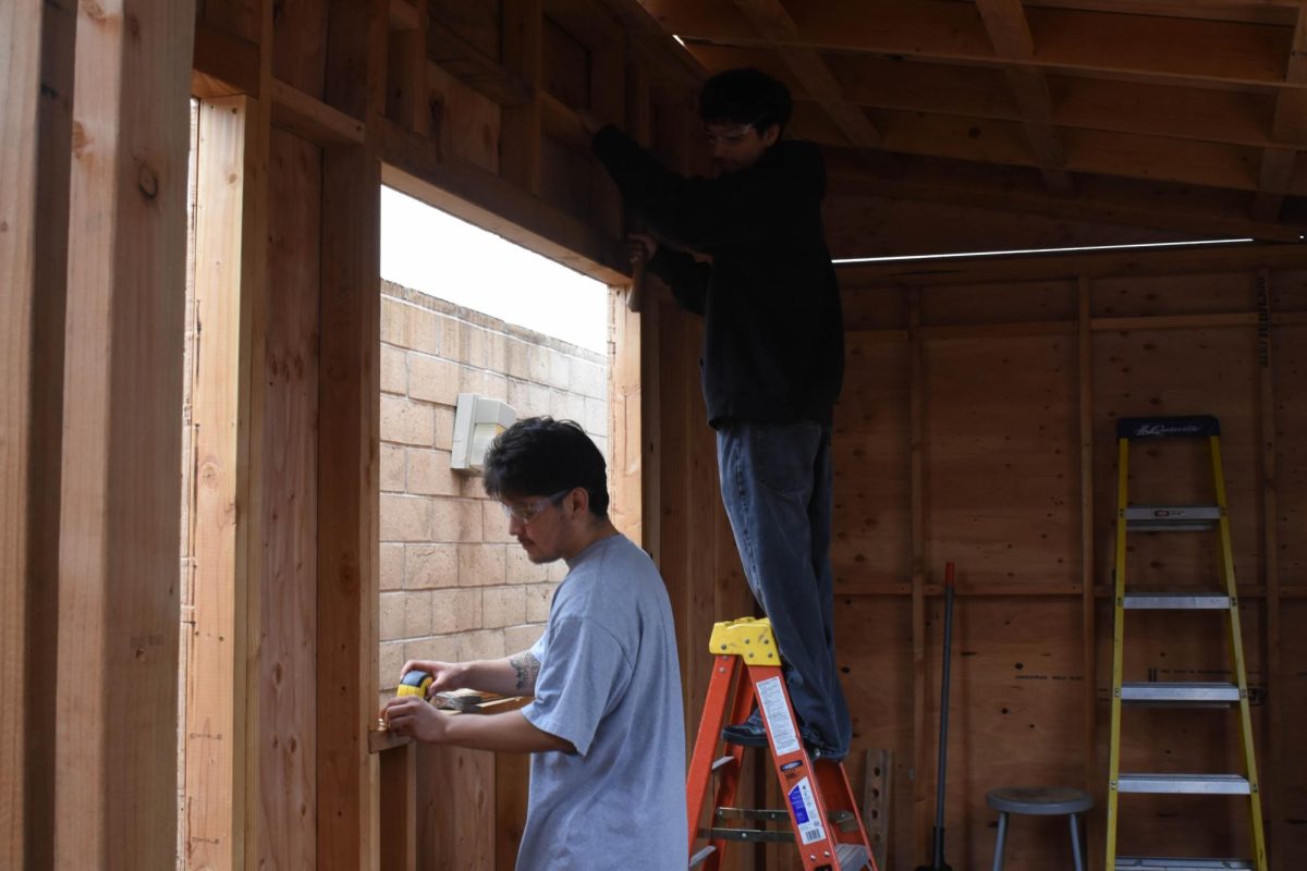 Jonathan Barroso (12) does measurements as Hector Lopez (12) holds a hammer and observes Barroso. This occurs during building class, BITA 1. In which they work on creating a sturdy built project in the making for a veterans home. 