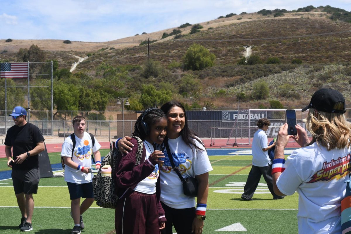 While preparing to exit the event, Stallion Olympic team instructor and athlete from the Stallion Team pose for a photo to capture a moment of completion. After completing multiple agile events, they pause and share an embrace for the photographer. Both proud of their team and accomplishments. 
