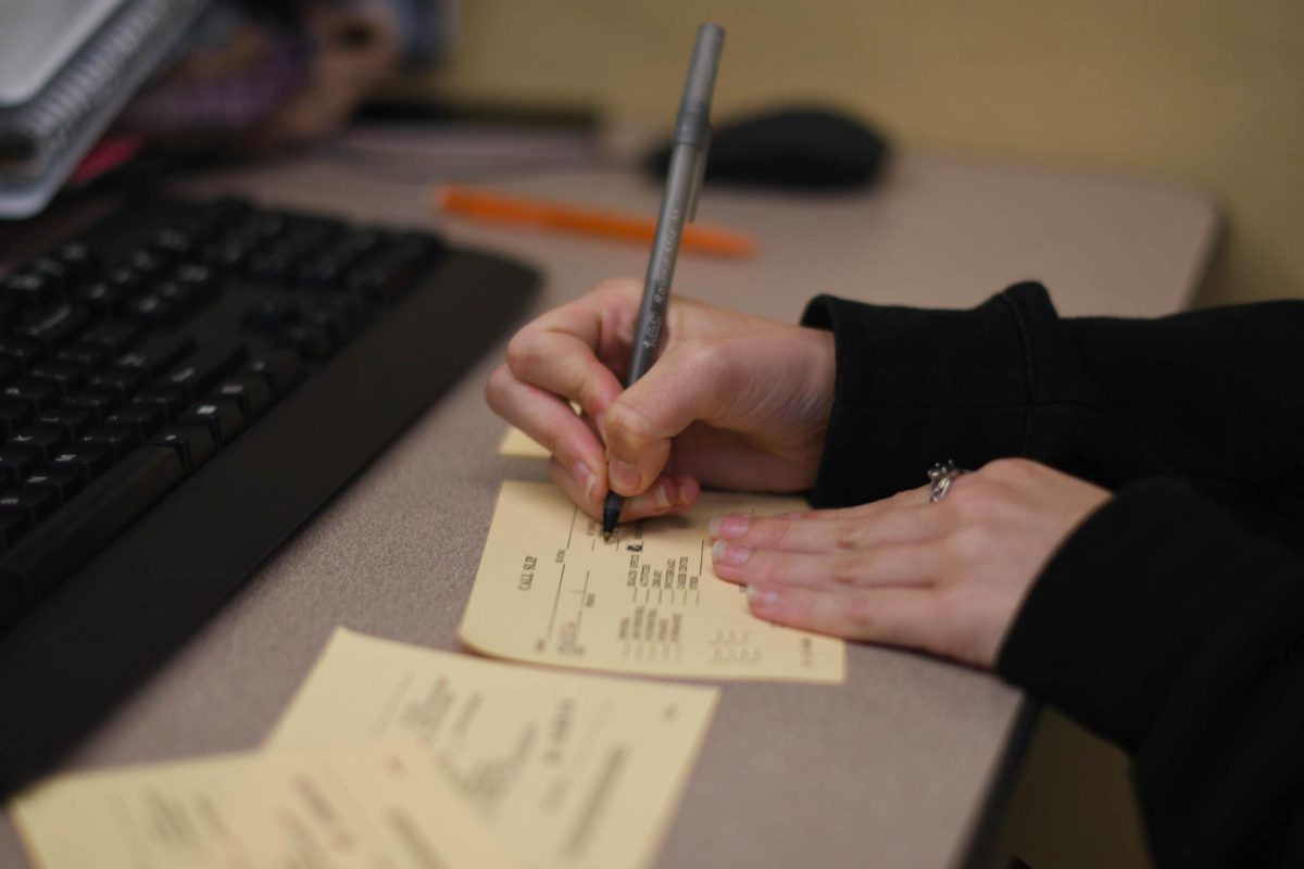 Behind the scenes of a member of The Express, Arts and Entertainment editor Caoimhin Grothe-Brinton (12) signs and fills out call slip for her next interviews. She fills out the students names and classrooms so she can pull them out of class and interview some topics for her recent story. 